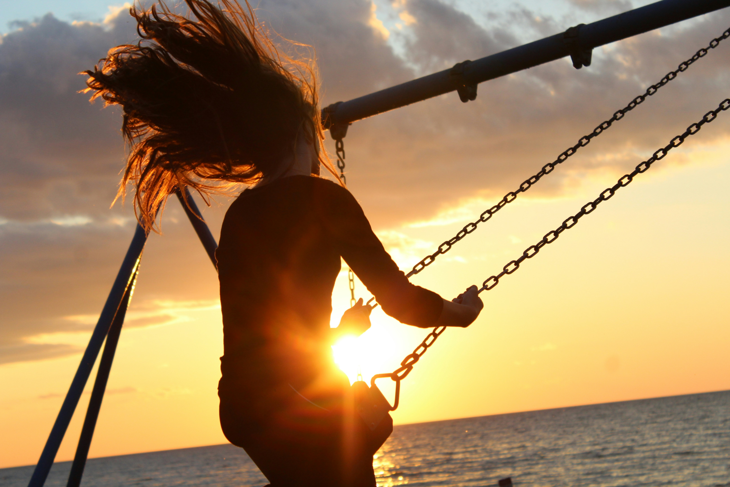 gratitude when feeling stuck - Woman swinging on swing while watching the sunset by the sea