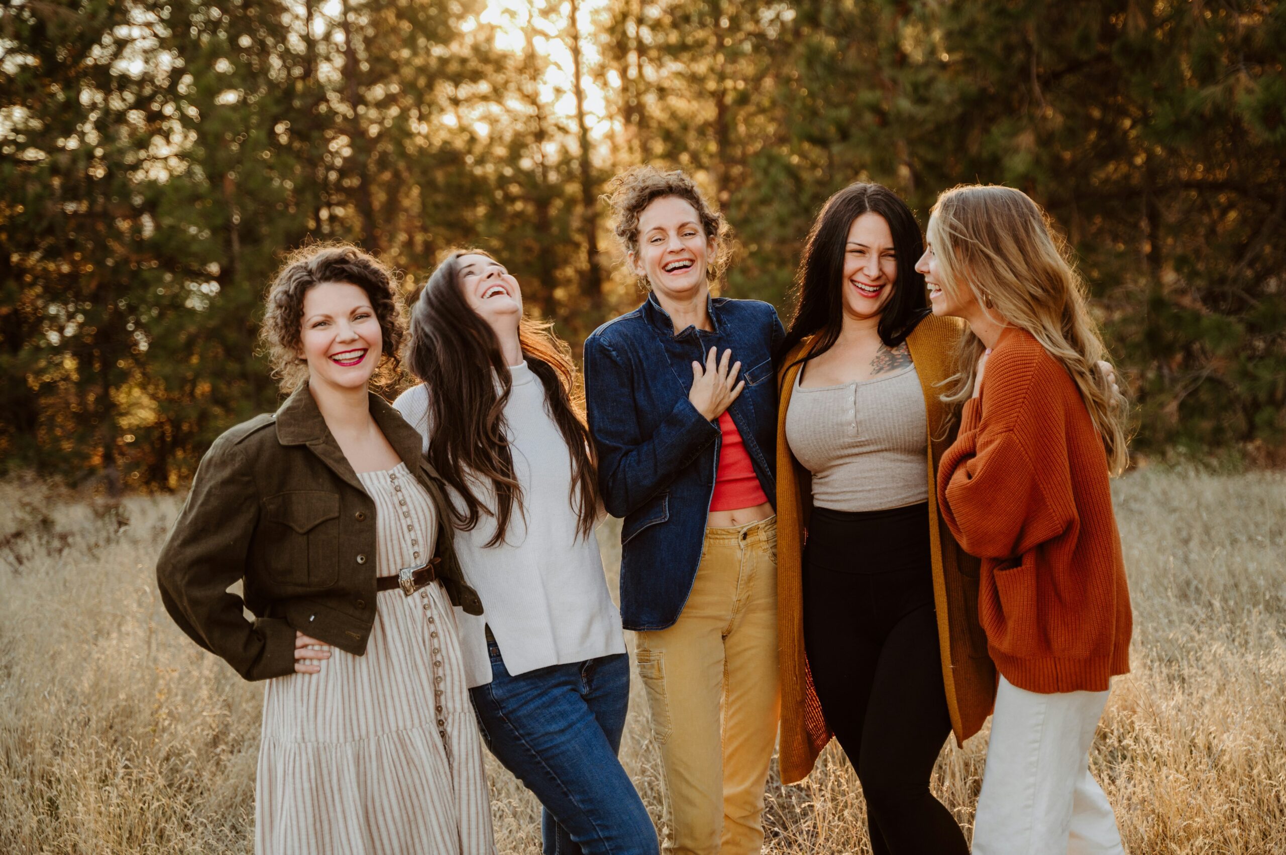 stop waiting for life to be perfect - 5 women laughing and enjoying each others company in a field in front of a forest at dusk