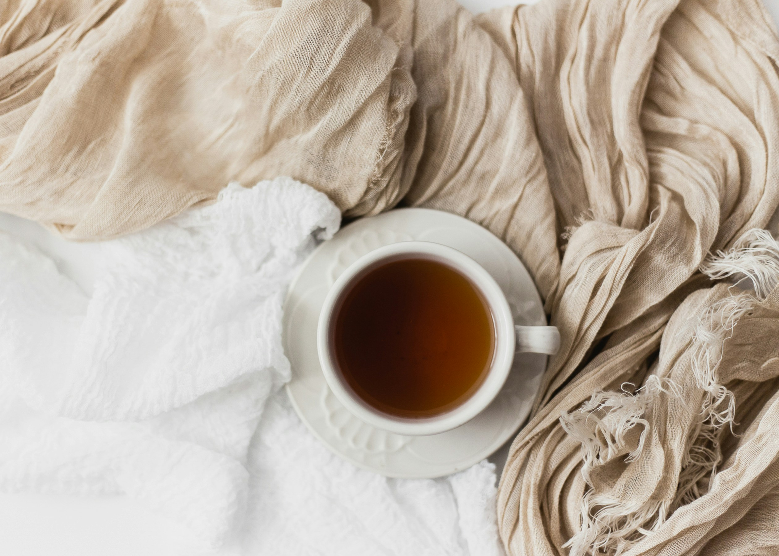 gratitude practices for anxiety - a cup of tea among bedsheets from above