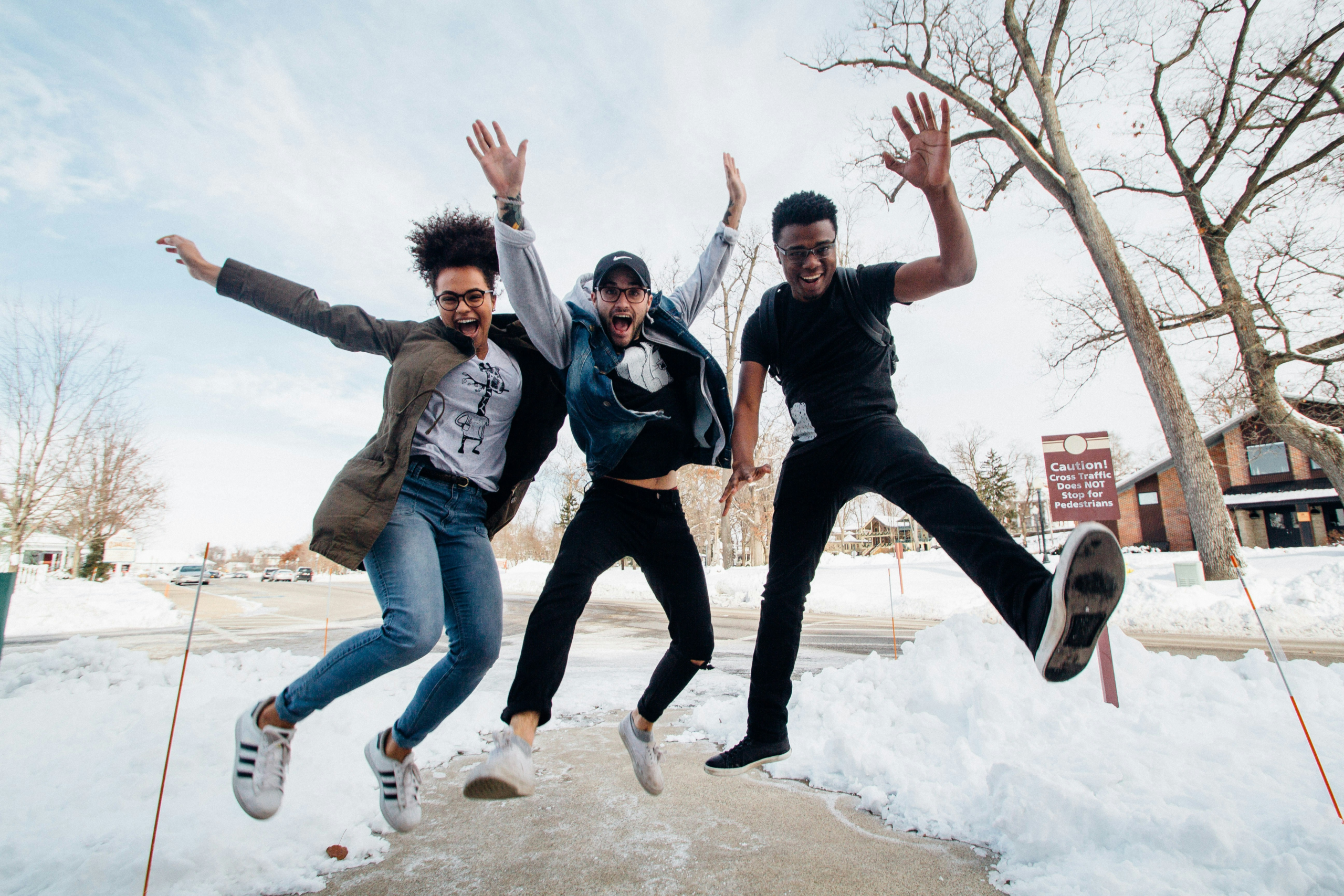 Friends enjoying a fun and joyful holiday season - Three friends jumping outside surrounded by snow