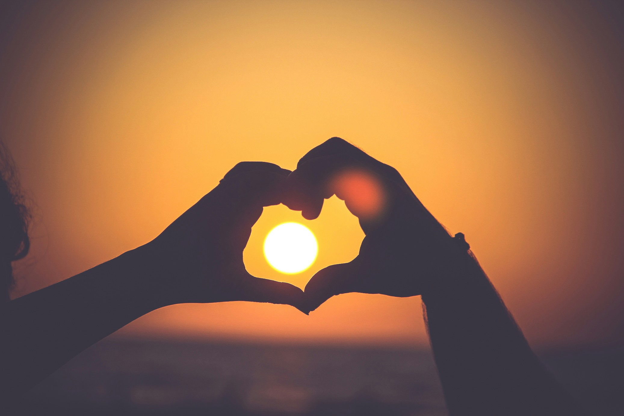 how to create a life you love - Hands framing the sun by forming a heart at sunset