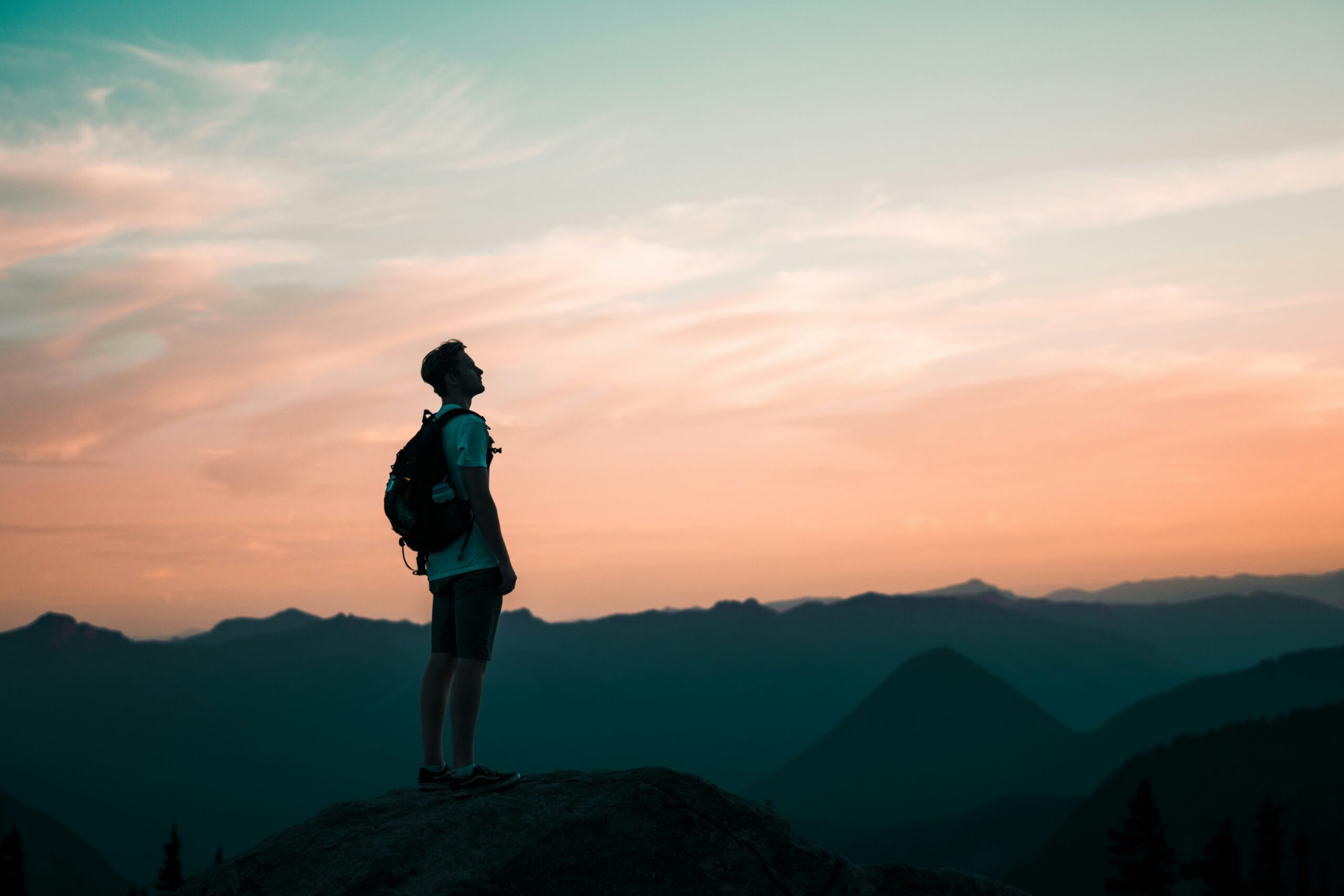 how to stay more positive when life is tough - man looking at the sky at sunset while on a hike