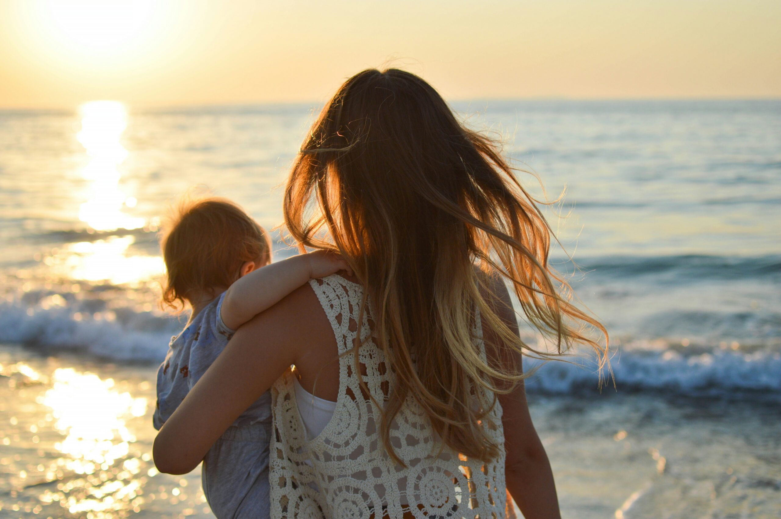 how to stop being so hard on yourself as a parent - mother holding her toddler while looking at the sea