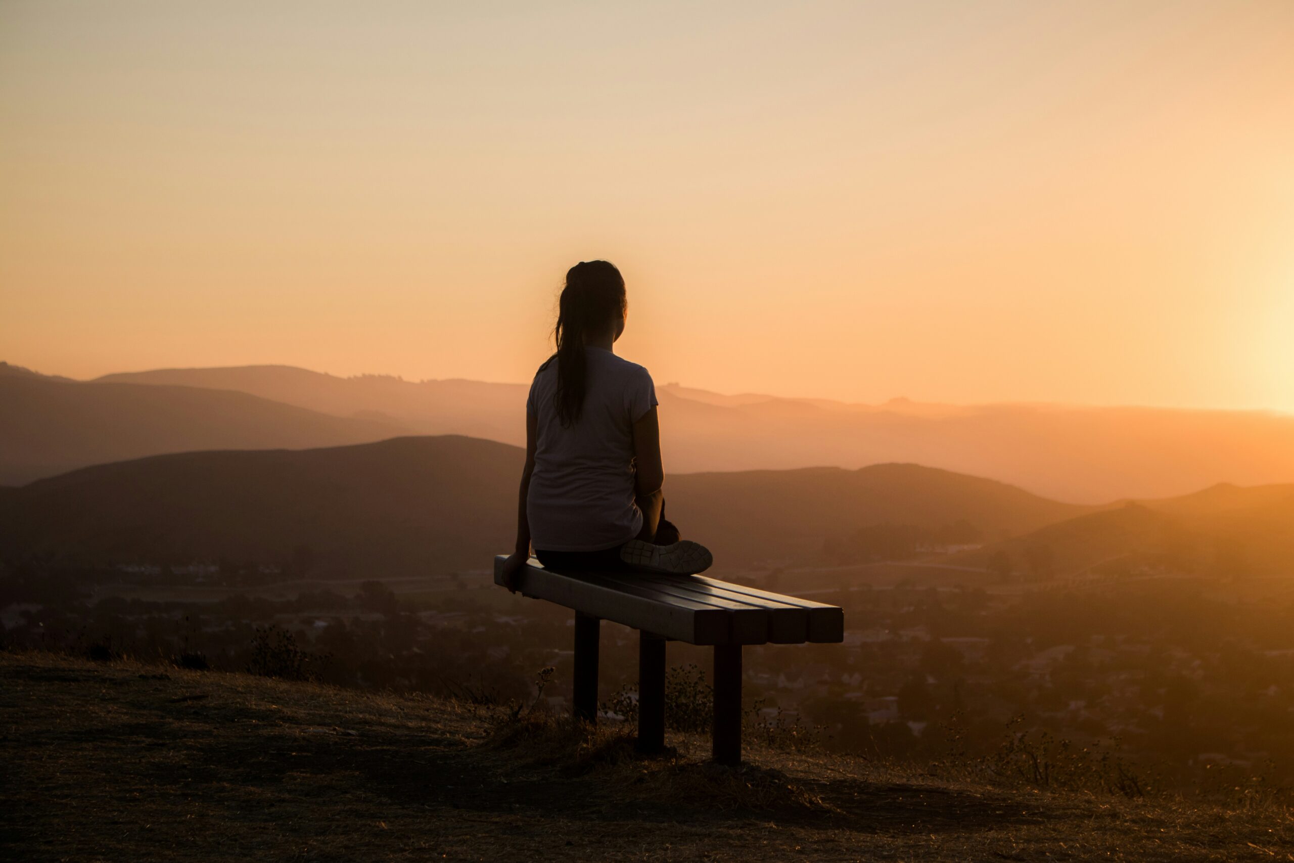 protect your energy - woman sitting on a scenic bench in the mountains at sunrise