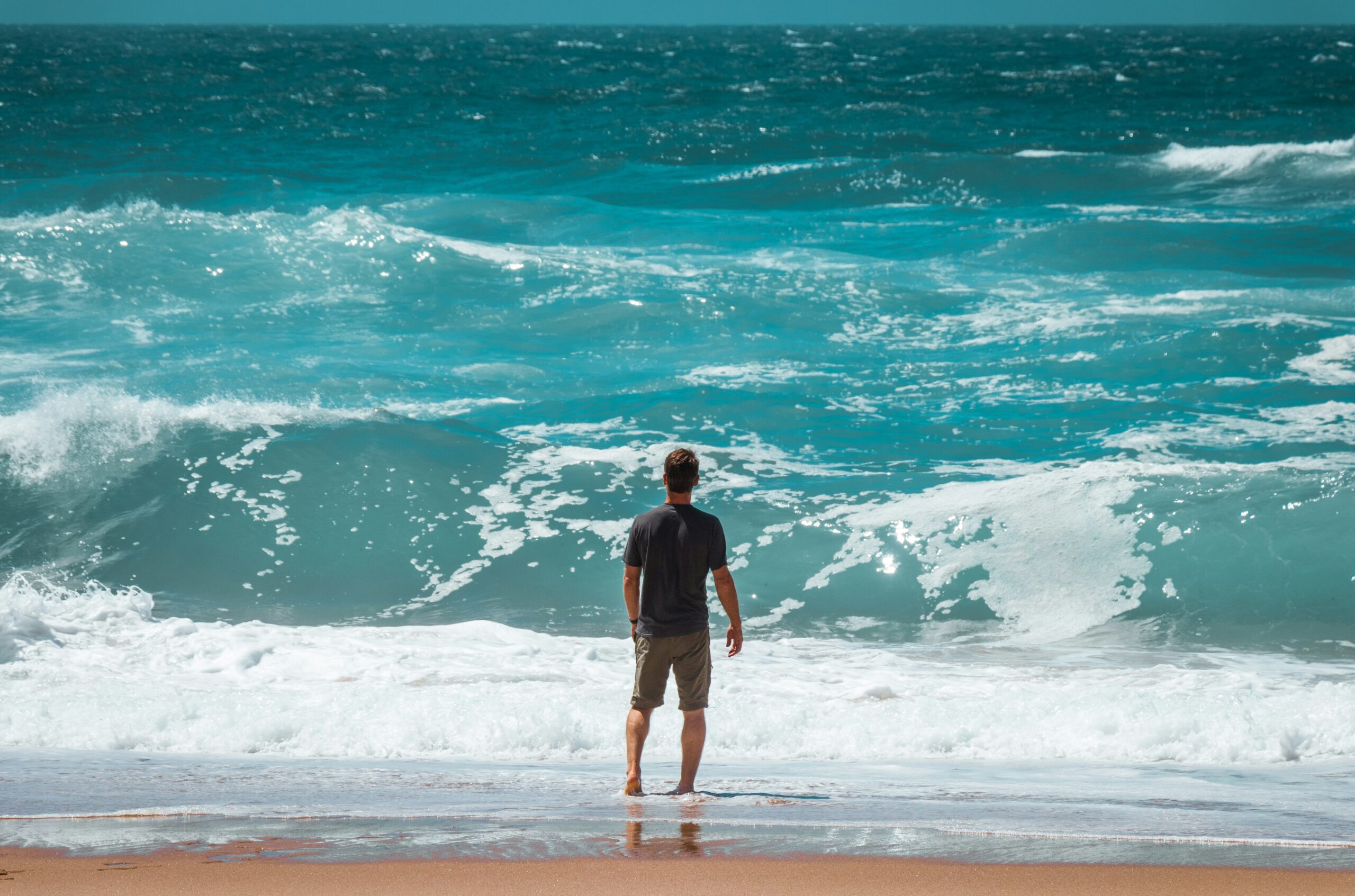 how to start over in life - man standing looking into the waves at the beach