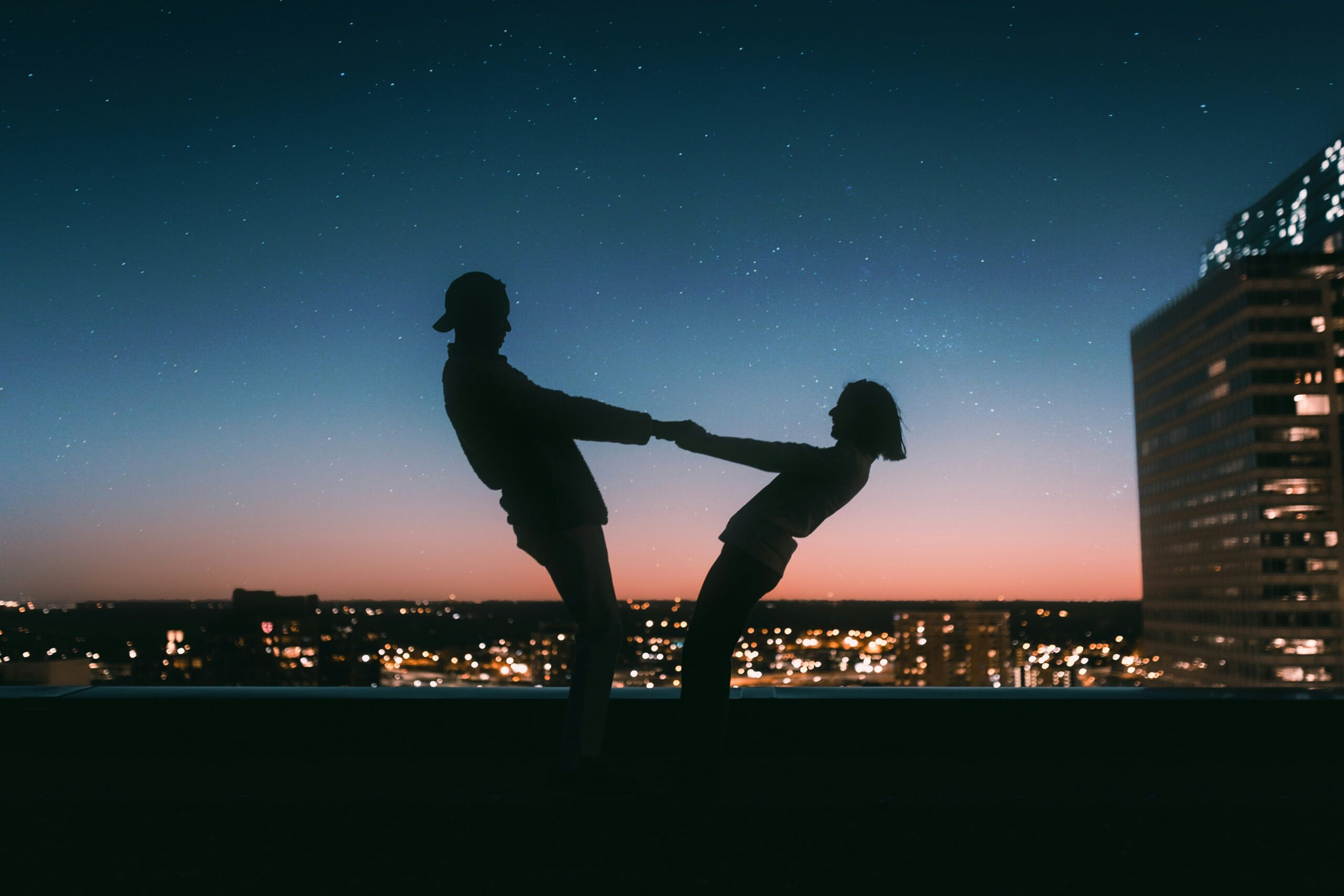 how to build the life you want - Couple holding hands at sunset overlooking city skyscrapers in urban scene.
