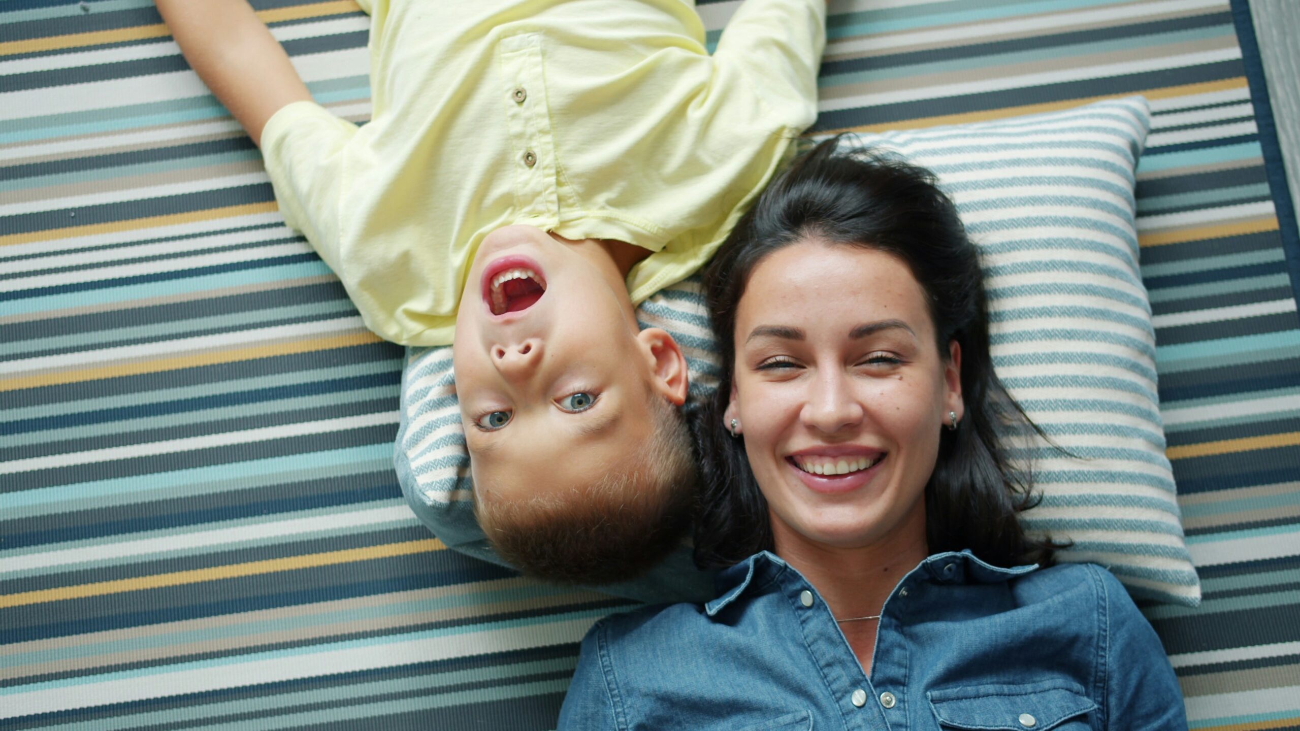 feel more positive as a parent - Mom and son laying down on a pillow and having a laugh